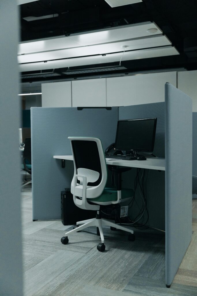 An empty modern office cubicle with a computer and swivel chair ready for work.